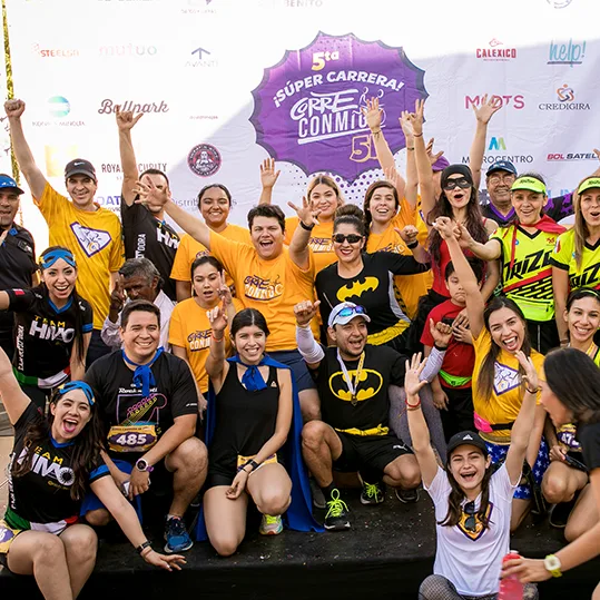 Equipo de Corre Conmigo celebrando en el escenario de la Súper Carrera